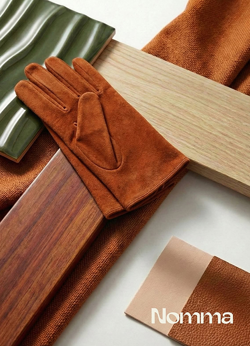 Composição de materiais em tons terracota, madeira e luva de camurça da marca Nomma.