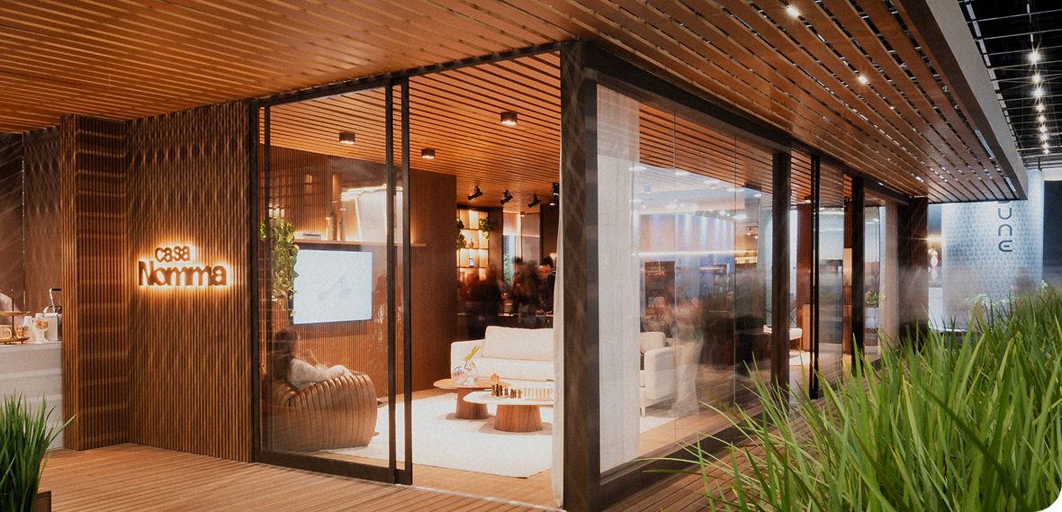 Fachada da Casa Nomma em madeira e vidro com iluminação aconchegante na Expo Revestir.