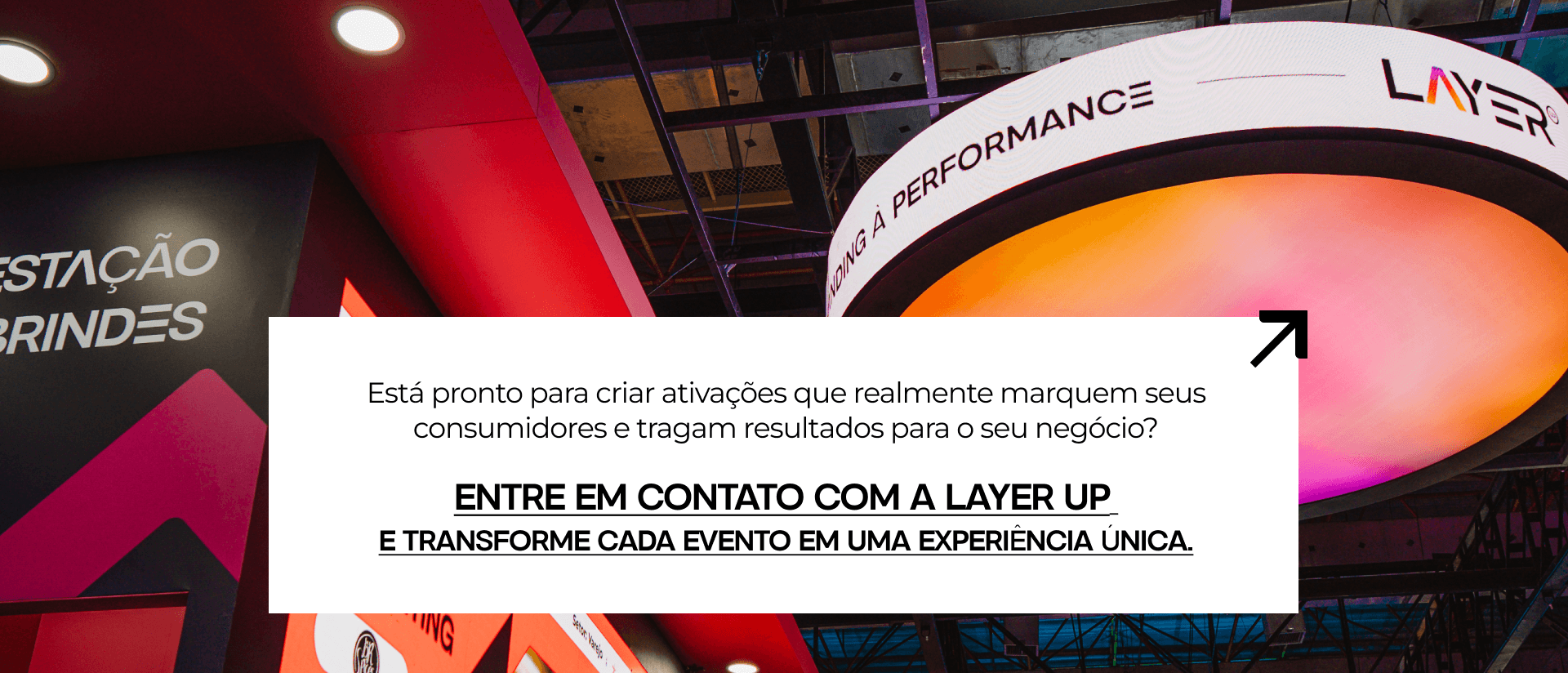 Banner promocional da Layer Up em um estande de evento com a frase "Está pronto para criar ativações que realmente marquem seus consumidores e tragam resultados para o seu negócio? Entre em contato com a Layer Up e transforme cada evento em uma experiência única."